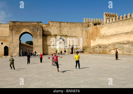 Moroccan Boys Playing Football in Bou Jeloud Town Square below Town or City Walls, Fez, Morocco Stock Photo