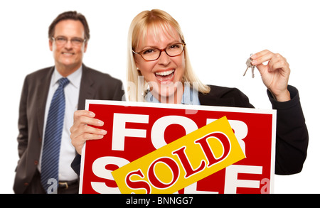 Man Behind with Attractive Blonde in Front Holding Keys and Sold For Sale Sign Isolated on a White Background. Stock Photo