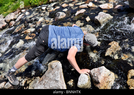 Man drinking water from stream. Valley of five ponds. Tatra's mountain. Stock Photo