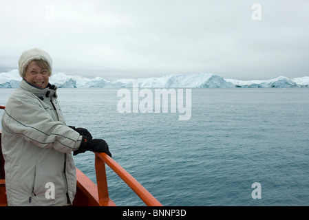 Mature lady watching icebergs close up from a small boat. Stock Photo