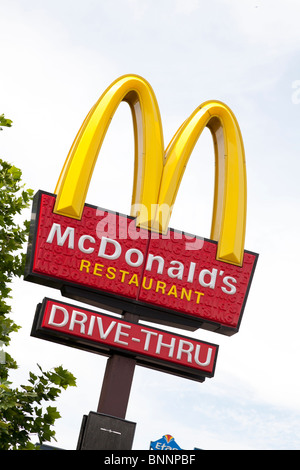 McDonald's sign and company logo on post with drive-thru sign at West Quay, Southampton. Stock Photo