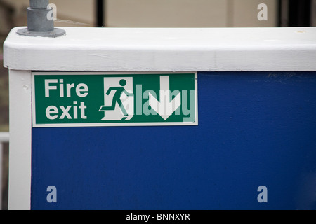 Fire exit sign, escape route sign, emergency exit sign, on blue wall of public house at Isle of Wight, Hampshire UK in May Stock Photo
