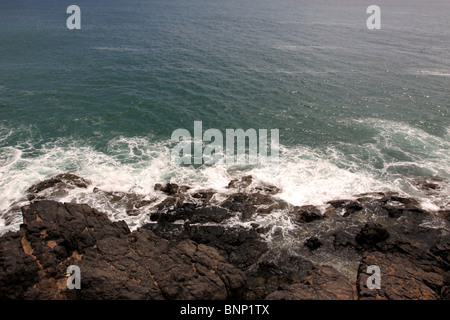 Waves crashing on rocks below small cliff Stock Photo