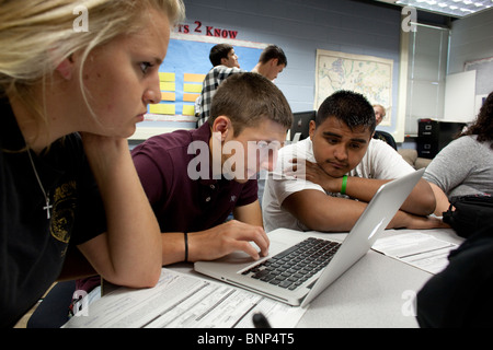Anglo and Hispanic students work together on a class project using a laptop computer to do research on the internet. Stock Photo