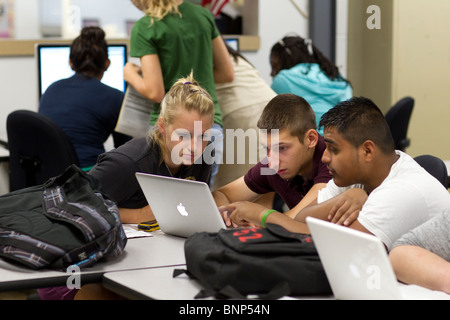 Anglo girl, boy, and Hispanic boy work together on class assignment using laptop computer and wireless internet to do research Stock Photo