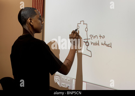 African-American boy draws plan of model solar car on interactive white board in engineering class at Manor New Tech High Stock Photo