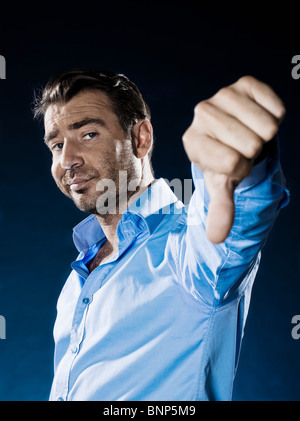 one caucasian man unshaven thumb down portrait isolated studio on black background Stock Photo