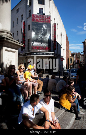 People sit near Cambridge Theatre, Seven Dials, Covent Garden, central London.