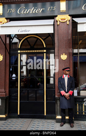 Shoppers pass high end shops on London's Bond Street. Known for it's exclusive fashion stores. Doorman at Cartier. Stock Photo