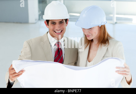 Two smiling engineers studying blueprints Stock Photo