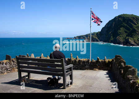 Old man and his dog enjoying the view from St. Nicholas chapel in Ilfracombe, North Devon Stock Photo