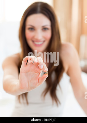 Smiling woman taking a pill sitting on bed Stock Photo