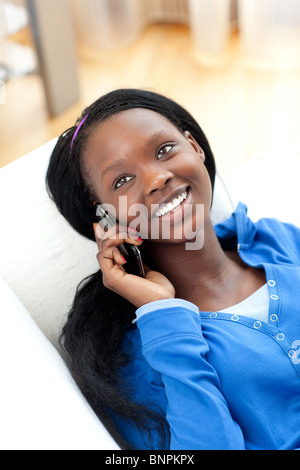Laughing woman on phone lying on a sofa Stock Photo