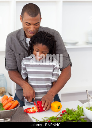 Attentive father helping his son cut vegetables Stock Photo