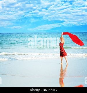 Beautiful woman walking near the ocean with red sarong Stock Photo