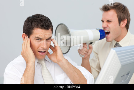 Businessman yelling through a megaphone at his colleague Stock Photo