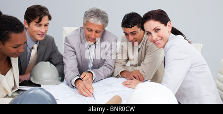 Beautiful female architect studying plans with her colleagues Stock Photo