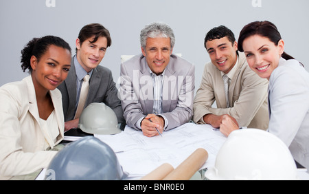 Smiling architects in a meeting studying plans Stock Photo