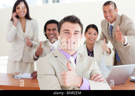 Successful manager in front of his team with thumbs up Stock Photo