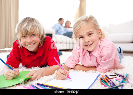 Lively siblings drawing lying on the floor Stock Photo