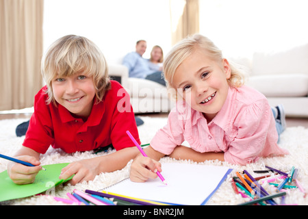 Happy siblings drawing lying on the floor Stock Photo