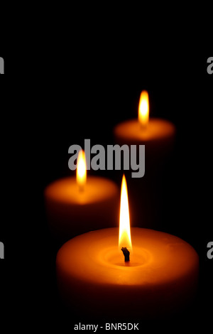 Three burning candles (focus on front candle) Stock Photo