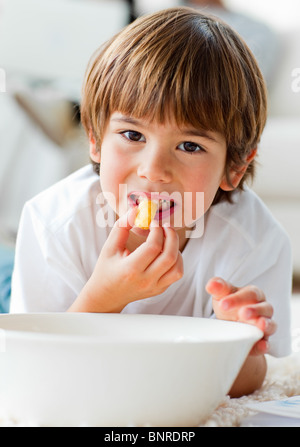 Cute little boy eating chips lying on the floor Stock Photo