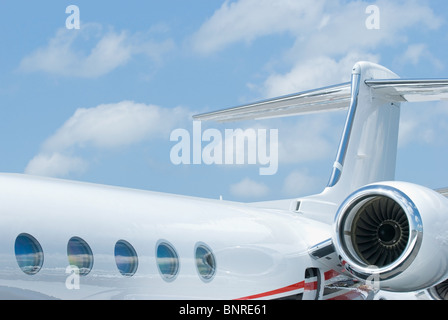 Rear section with tail and engine of white corporate jet with oval windows Stock Photo