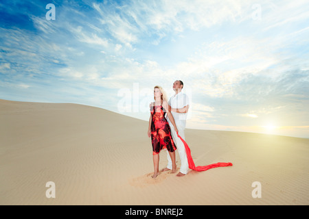 Young beautiful couple in desert at sunrise time Stock Photo