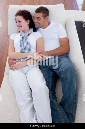 Couple lying on sofa watching television Stock Photo