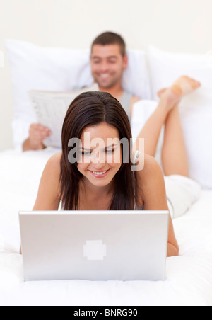 Woman using a laptop and man reading a newspaper Stock Photo
