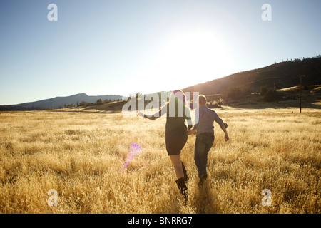 Couple hold hands and run together in an open field. Stock Photo