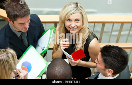 Smiling businesswoman working with her colleagues on stairs Stock Photo