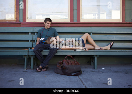 Young couple sitting on the bench waiting for the bus. Stock Photo