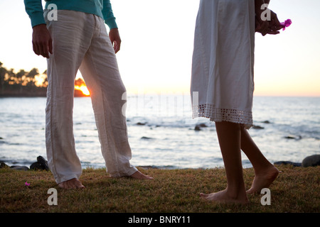 A man talks with a shy woman near the ocean at sunset. Stock Photo