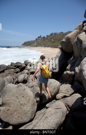 A woman hiking along a rocky coastline. Stock Photo