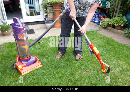 Vacuuming the grass lawn with a Dyson vacuum cleaner Stock Photo