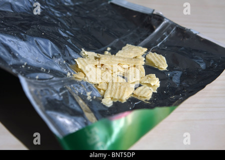 a few bits of crisps left in a torn open crisp bag Stock Photo