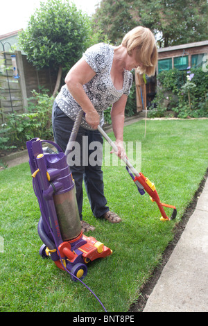 Vacuuming the grass lawn with a Dyson vacuum cleaner Stock Photo