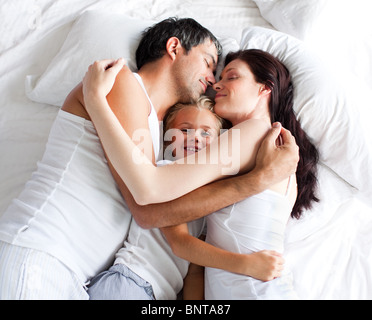 Parents and daughter relaxing on bed Stock Photo
