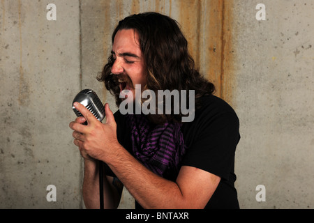 Portrait of young man singing into vintage microphone Stock Photo
