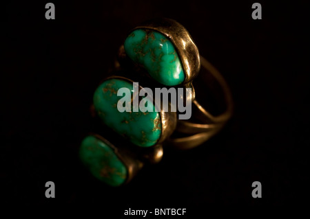 An Indian silver ring set with three turquoise stones on a dark brown background. Stock Photo