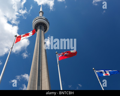 Toronto, Ontario and Canada flags flying in front of CN tower over blue sky Stock Photo