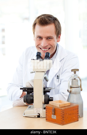 Smiling scientist looking through a microscope Stock Photo