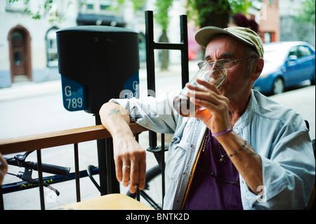 Old man finishes a pint of beer while sitting on bar terrace. Stock Photo