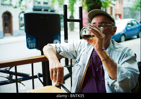 Old man finishes a pint of beer while sitting on bar terrace. Stock Photo