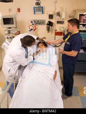 An African American emergency room physician (left) examines teen drug overdose victim at Orange, California, with med tech. Stock Photo