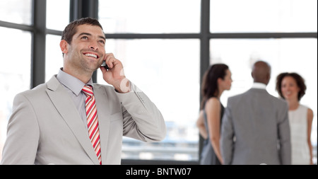 Handsome businessman on phone in office with his team Stock Photo