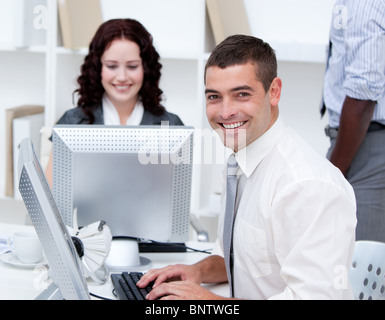 Smiling young business people working at computers Stock Photo