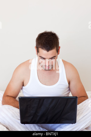 Nice  man using a laptop in his bedroom Stock Photo